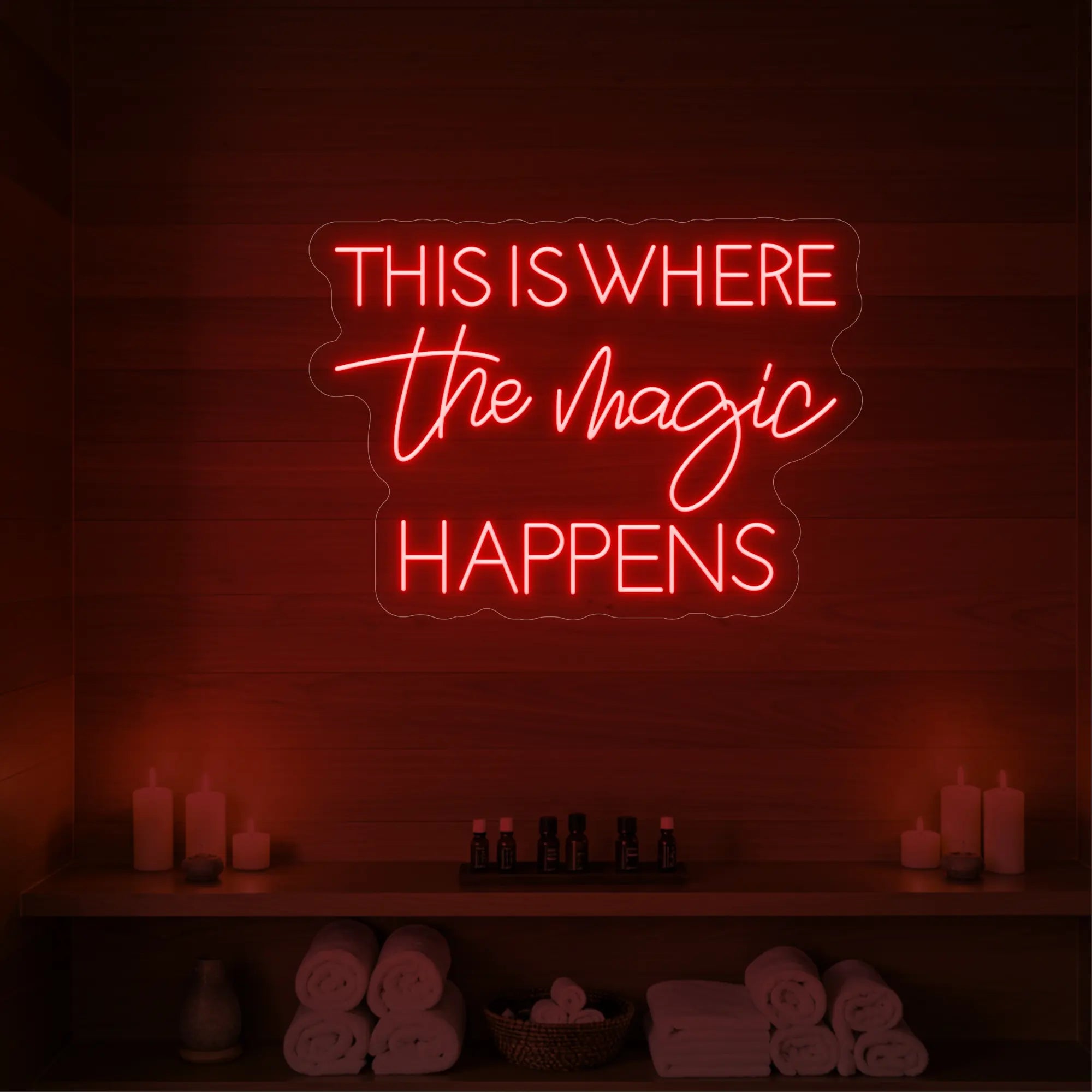 Photo of the 'This Is Where The Magic Happens' neon sign glowing in red against a styled interior wall.