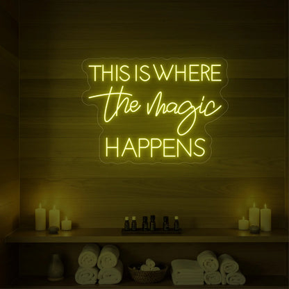 Photo of the 'This Is Where The Magic Happens' neon sign glowing in lemon yellow against a styled interior wall.