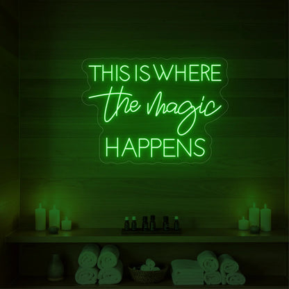 Photo of the 'This Is Where The Magic Happens' neon sign glowing in green against a styled interior wall.