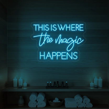 Photo of the 'This Is Where The Magic Happens' neon sign glowing in ice blue against a wooden spa wall.