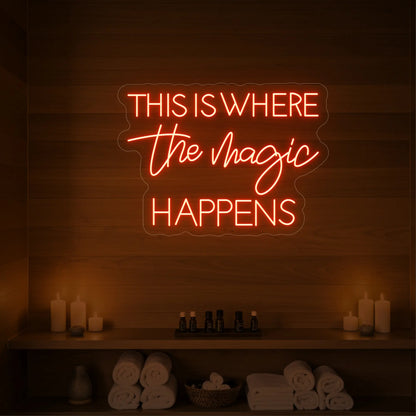 Photo of the 'This Is Where The Magic Happens' neon sign glowing in golden yellow against a styled interior wall.