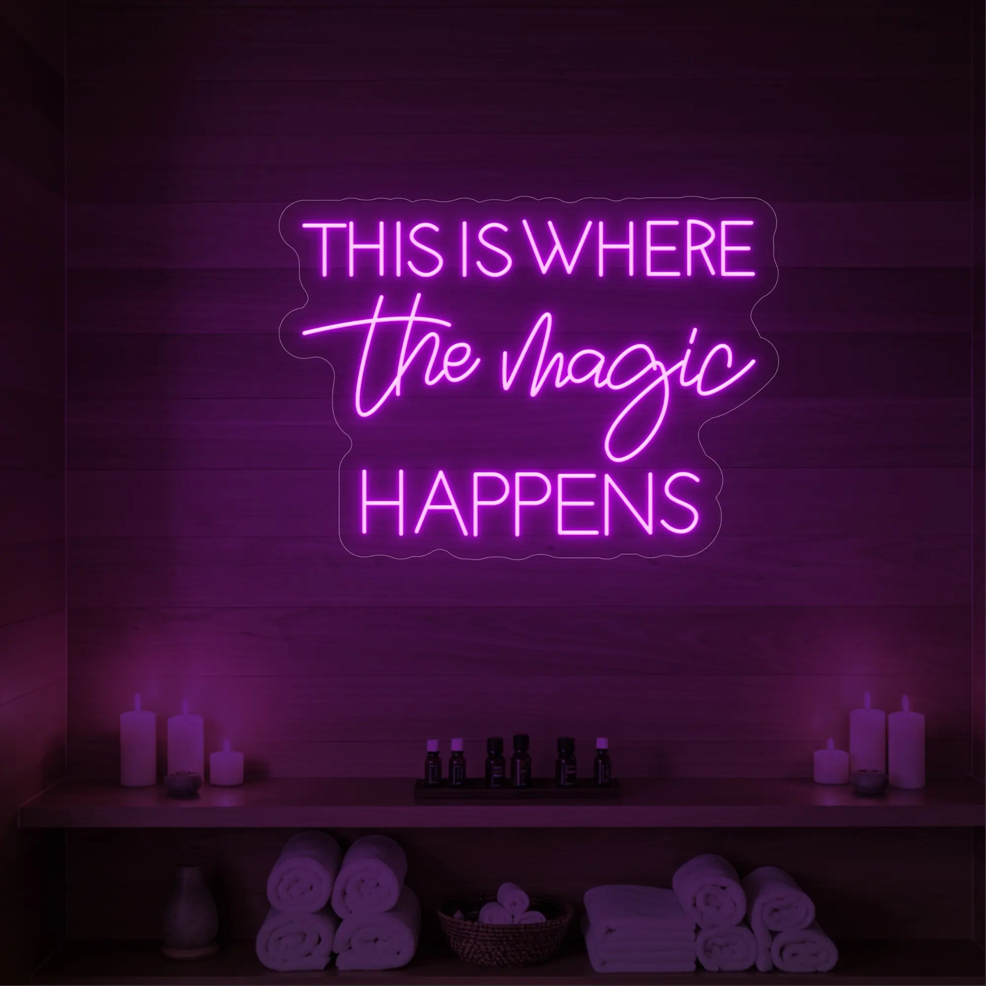 Photo of the 'This Is Where The Magic Happens' neon sign glowing in deep pink against a styled interior wall.