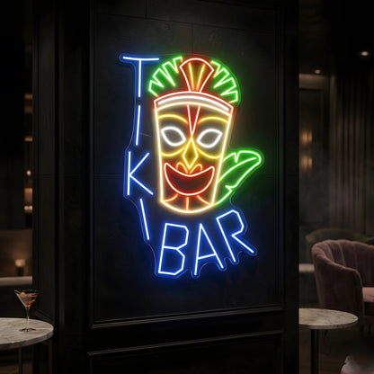 Photo of the 'Tiki Bar' neon sign glowing in multi-color against a tropical tiki-inspired wall.