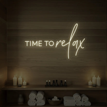 Photo of the 'TIME TO RELAX' neon sign glowing in warm white against a styled interior wall.