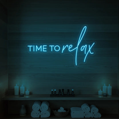 Photo of the 'TIME TO RELAX' neon sign glowing in ice blue against a styled interior wall.
