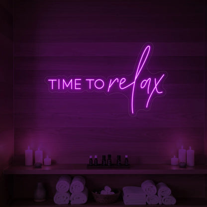 Photo of the 'TIME TO RELAX' neon sign glowing in deep pink against a styled interior wall.
