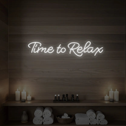 Photo of the 'Time to Relax' neon sign glowing in cool white against a styled interior wall.