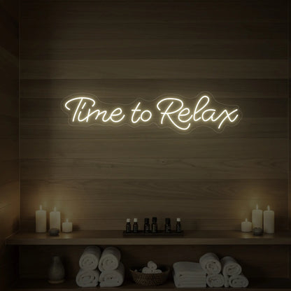 Photo of the 'Time to Relax' neon sign glowing in warm white against a styled interior wall.