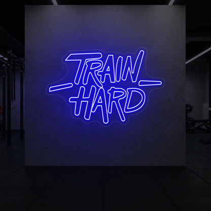 'TRAIN HARD' neon sign glowing in deep blue against a styled interior wall.