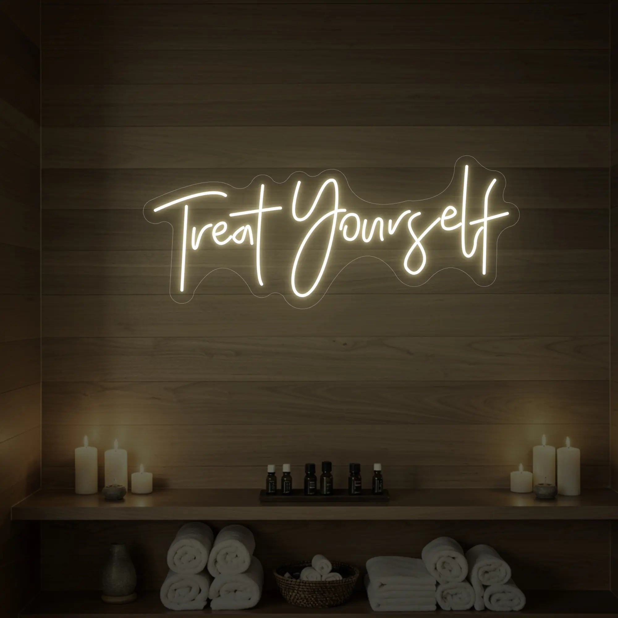 Photo of the 'Treat Yourself' neon sign glowing in warm white against a styled interior wall.