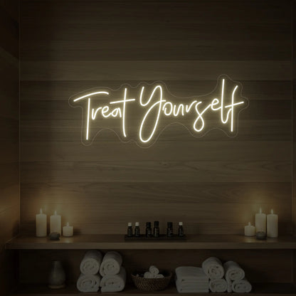 Photo of the 'Treat Yourself' neon sign glowing in warm white against a styled interior wall.