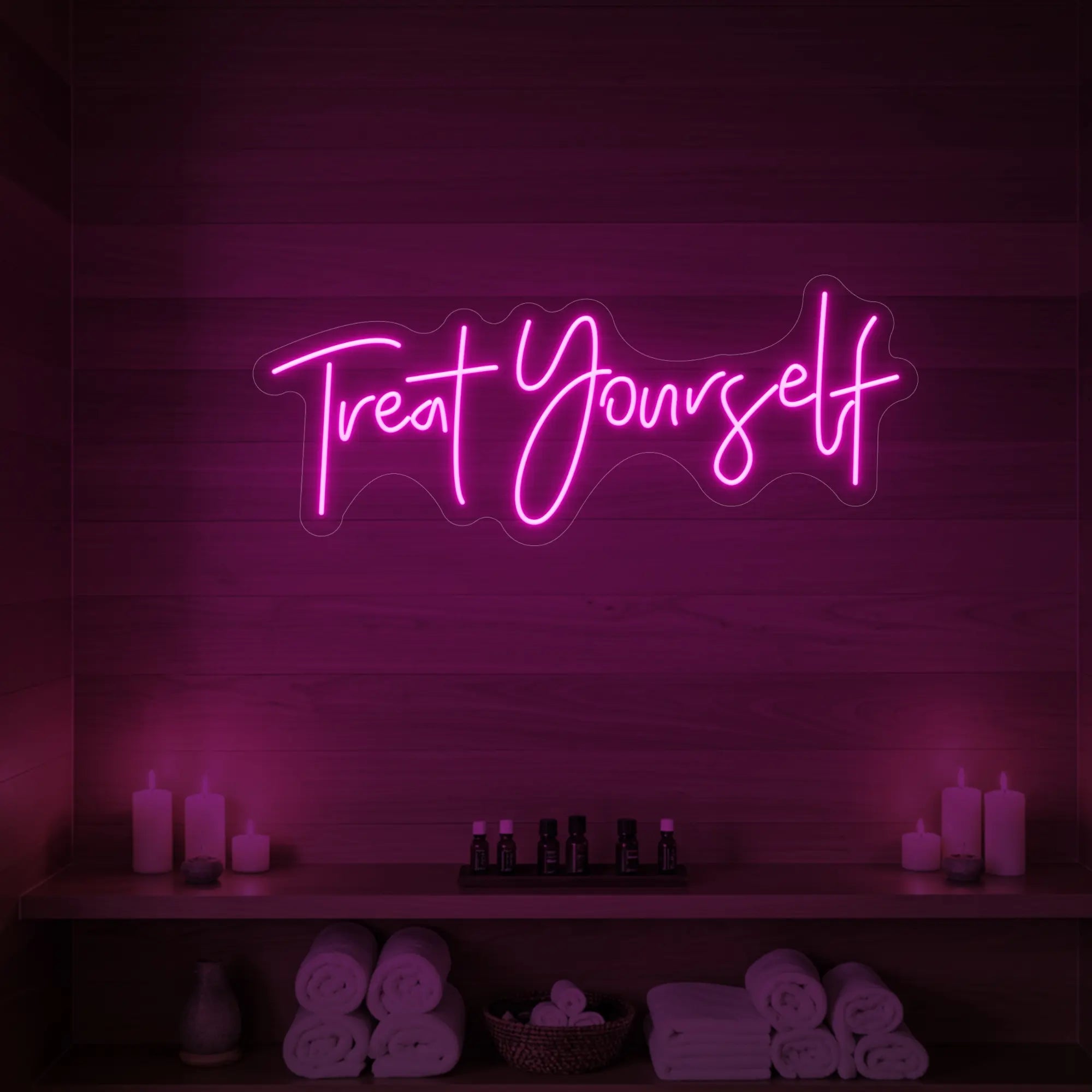 Photo of the 'Treat Yourself' neon sign glowing in light pink against a styled interior wall.