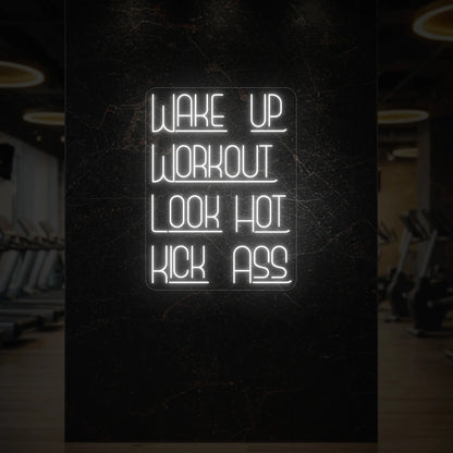  'WAKE UP WORKOUT LOOK HOT KICK ASS' neon sign glowing in cool white against a styled interior wall.