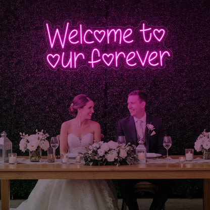  'Welcome To Our Forever' neon sign glowing in light pink against a styled interior wall.