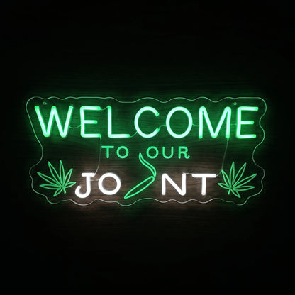 Welcome To Your Joint LED neon sign featuring green and white lettering with cannabis leaves and a pre-roll graphic on a clear acrylic backing.