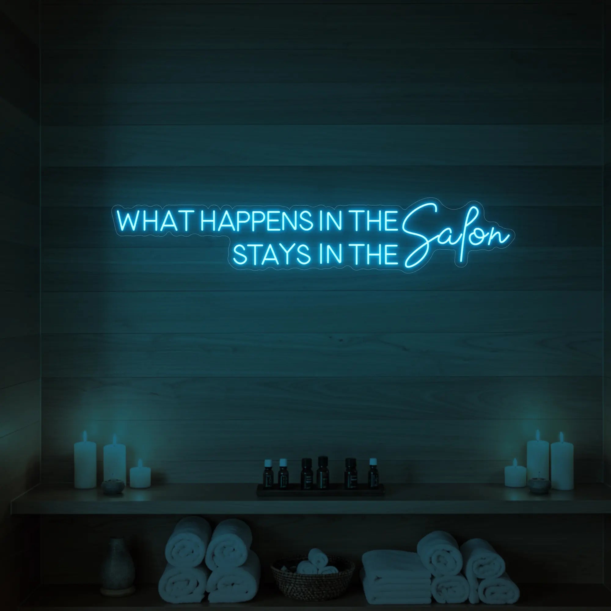 Photo of the 'WHAT HAPPENS IN THE SALON STAYS IN THE SALON' neon sign glowing in ice blue against a styled interior wall.
