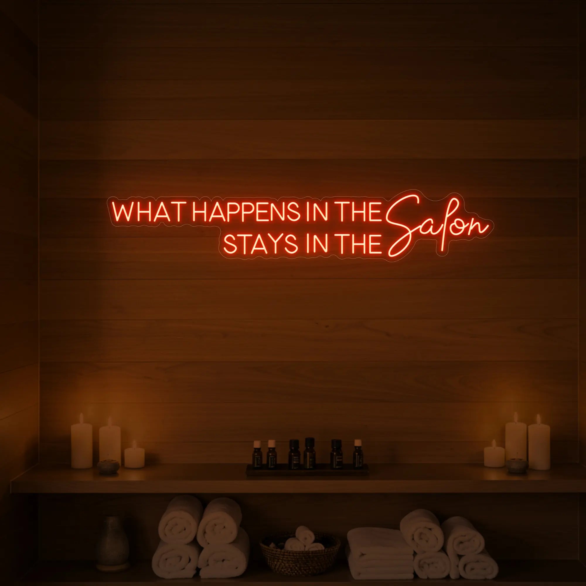 Photo of the 'WHAT HAPPENS IN THE SALON STAYS IN THE SALON' neon sign glowing in golden yellow against a styled interior wall.