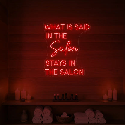 Photo of the 'What is Said in the Salon Stays in the Salon' neon sign glowing in red against a styled interior wall.