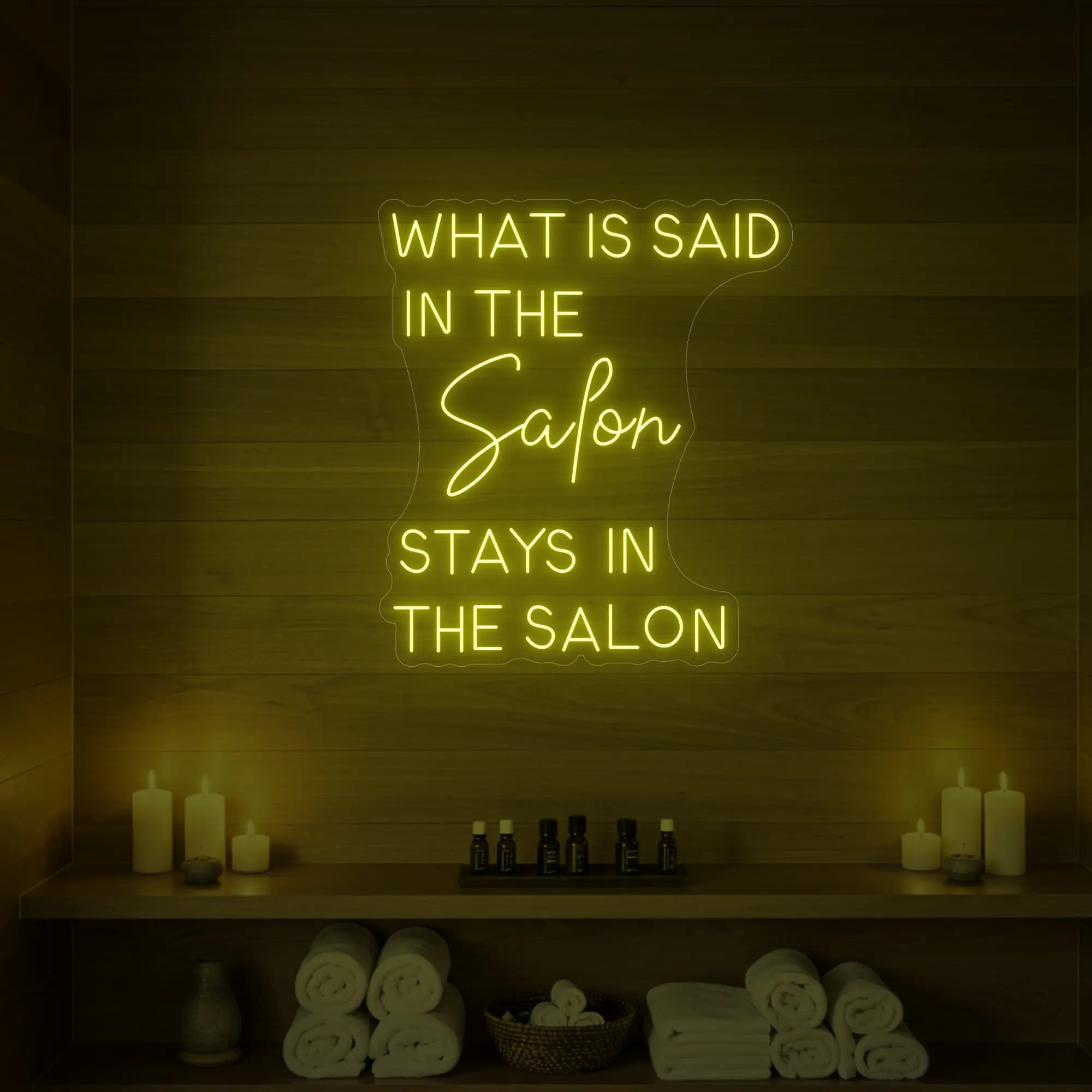 Photo of the 'What is Said in the Salon Stays in the Salon' neon sign glowing in lemon yellow against a styled interior wall.