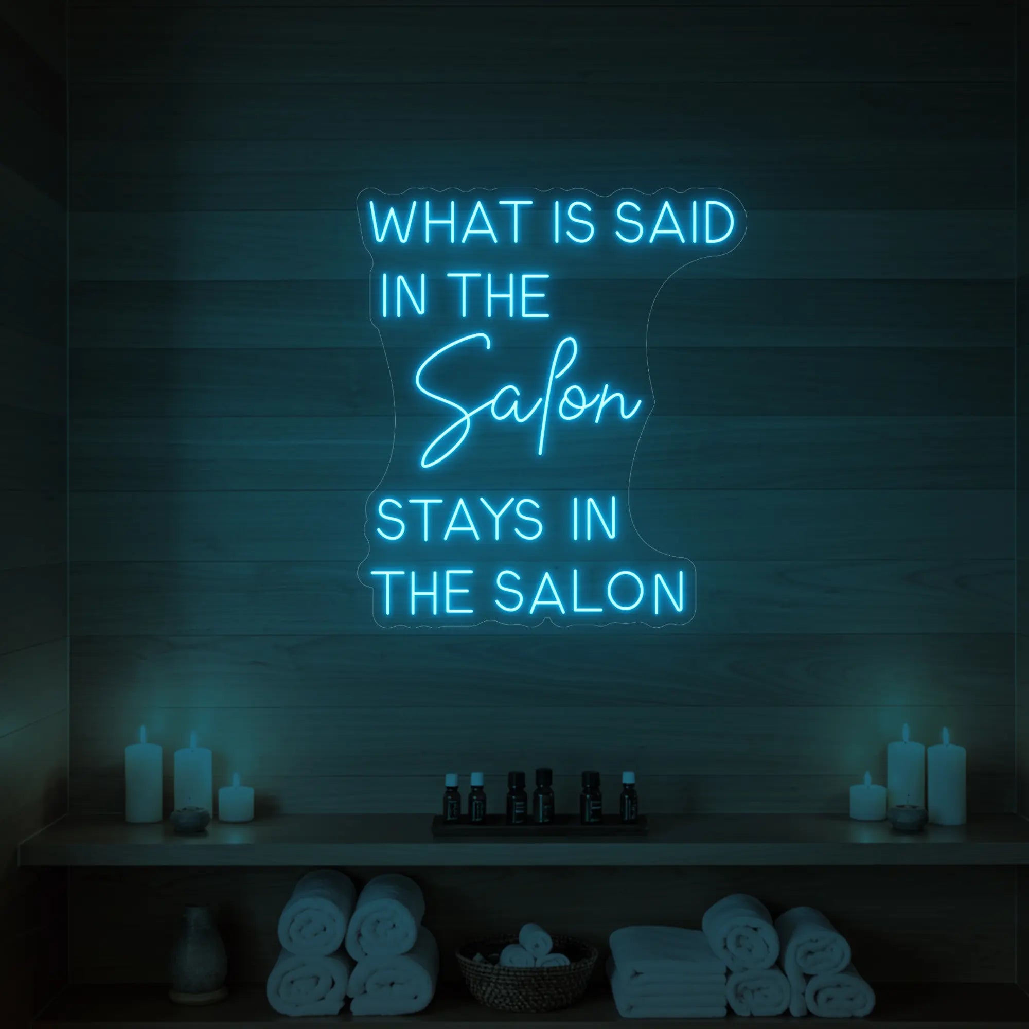 Photo of the 'What is Said in the Salon Stays in the Salon' neon sign glowing in ice blue against a styled interior wall.