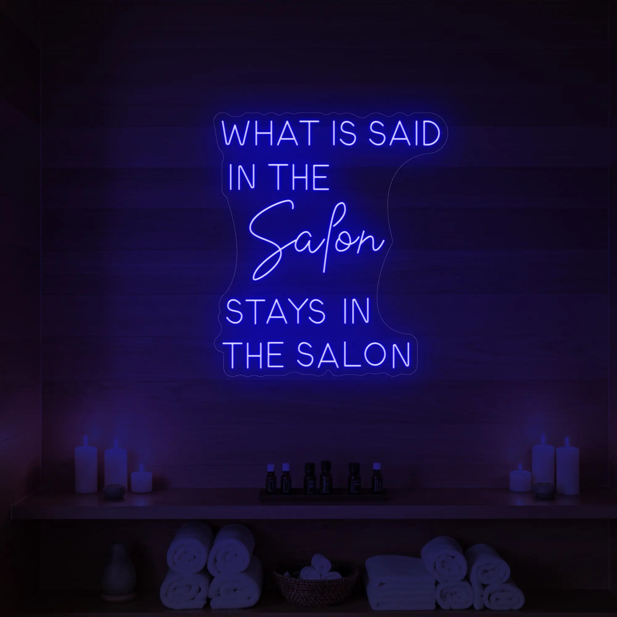 Photo of the 'What is Said in the Salon Stays in the Salon' neon sign glowing in deep blue against a styled interior wall.