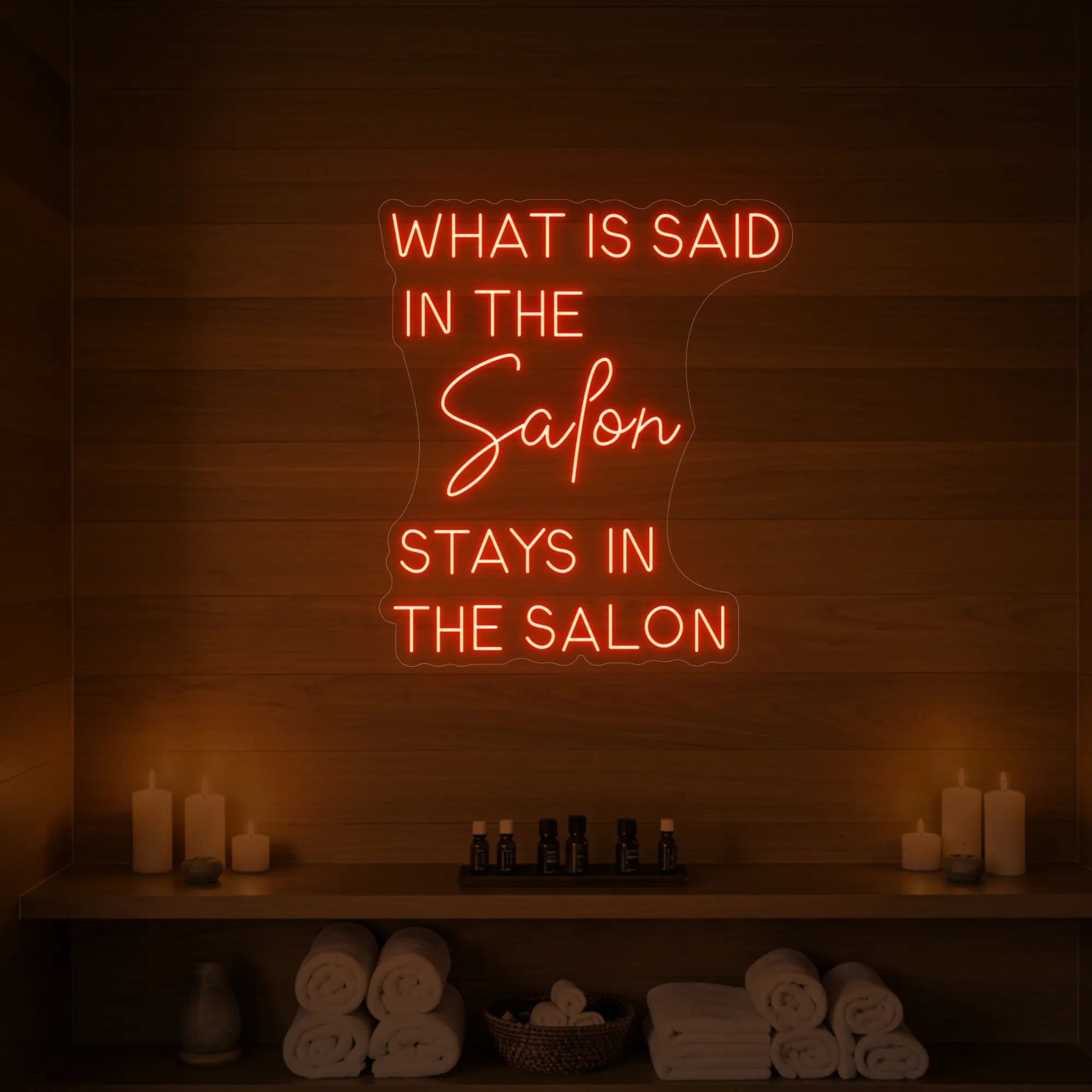 Photo of the 'What is Said in the Salon Stays in the Salon' neon sign glowing in golden yellow against a styled interior wall.