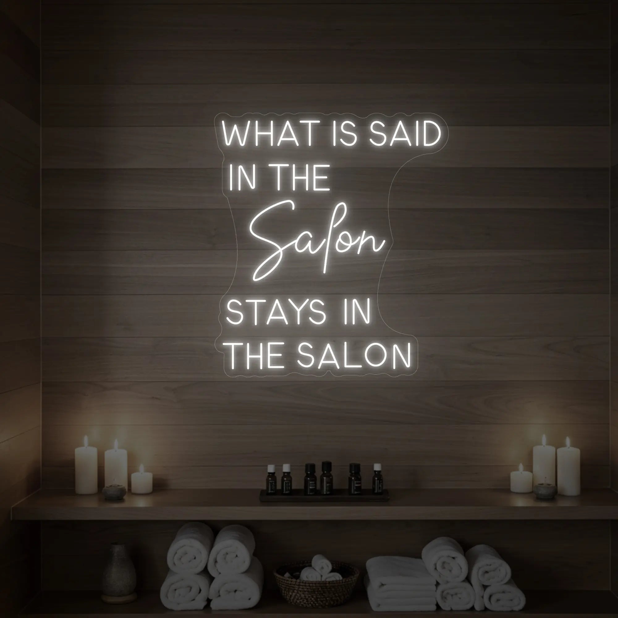 Photo of the 'What is Said in the Salon Stays in the Salon' neon sign glowing in cool white against a styled interior wall.