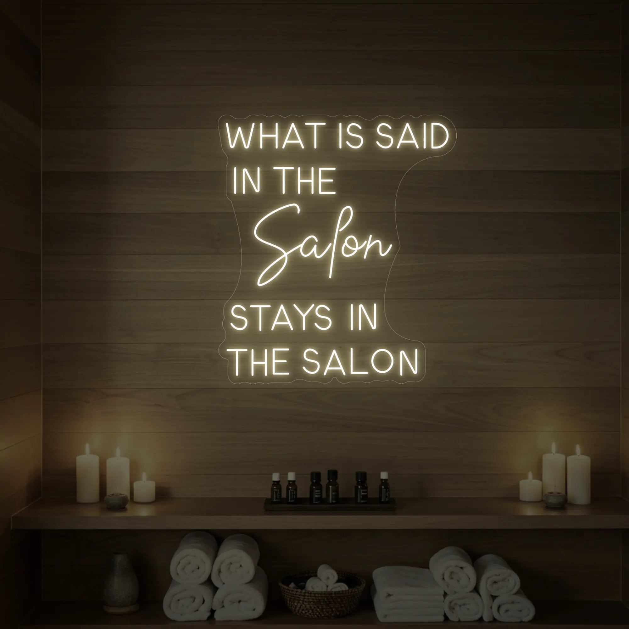Photo of the 'What is Said in the Salon Stays in the Salon' neon sign glowing in warm white against a styled interior wall.