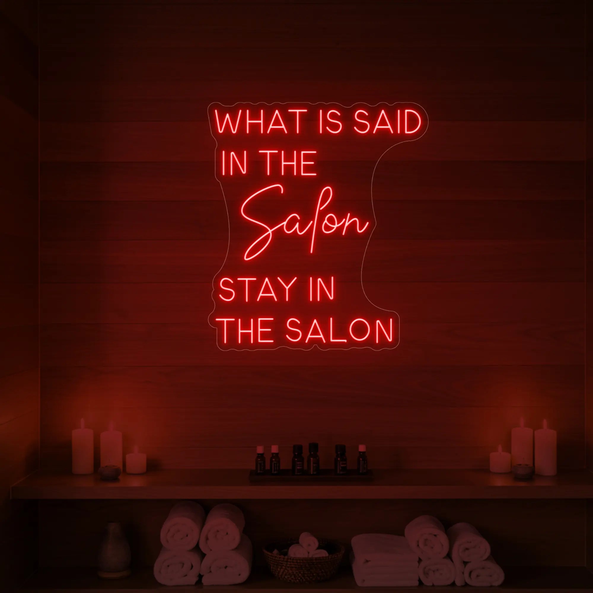 Photo of the 'WHAT IS SAID IN THE SALON STAY IN THE SALON' neon sign glowing in red against a styled interior wall.