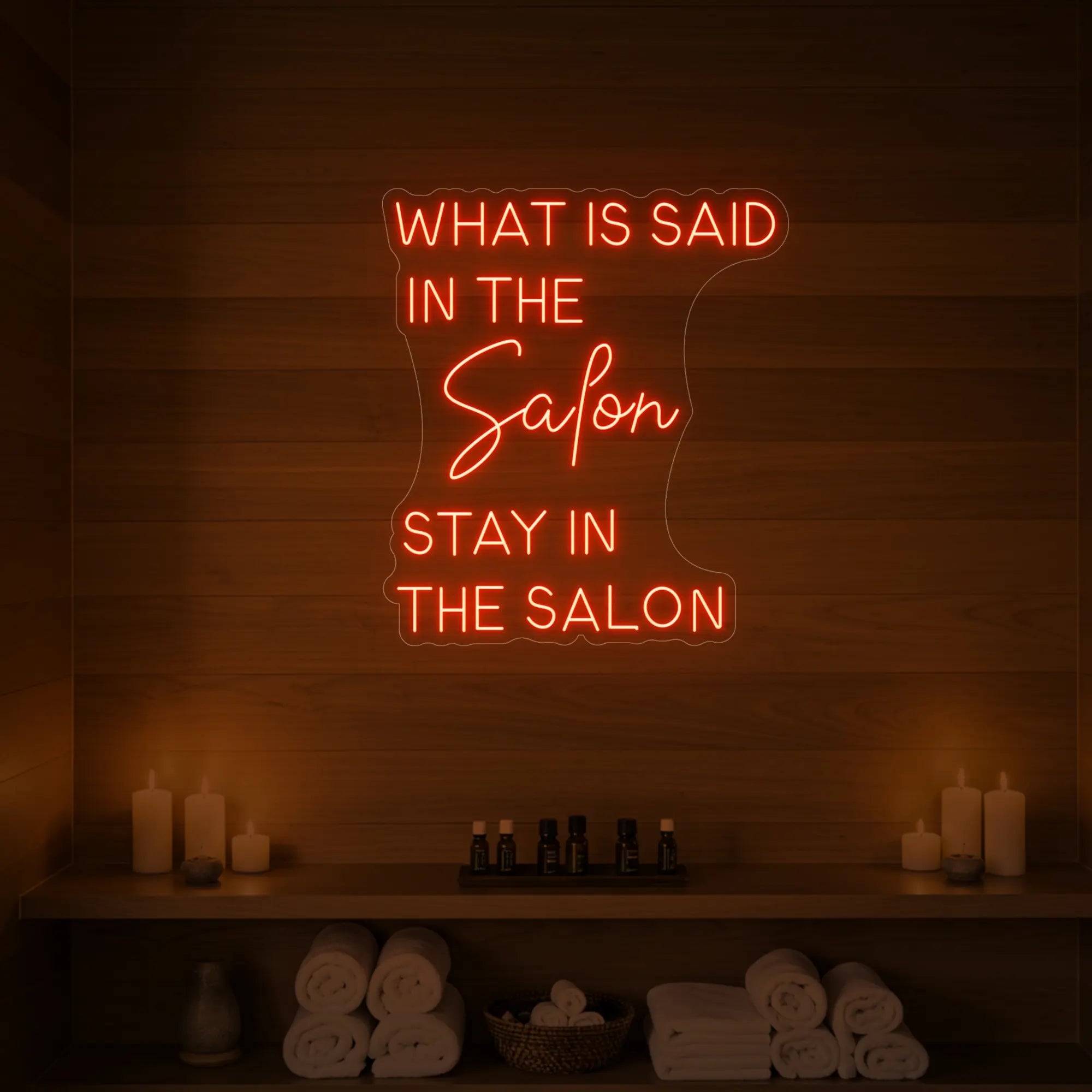 Photo of the 'WHAT IS SAID IN THE SALON STAY IN THE SALON' neon sign glowing in golden yellow against a styled interior wall.