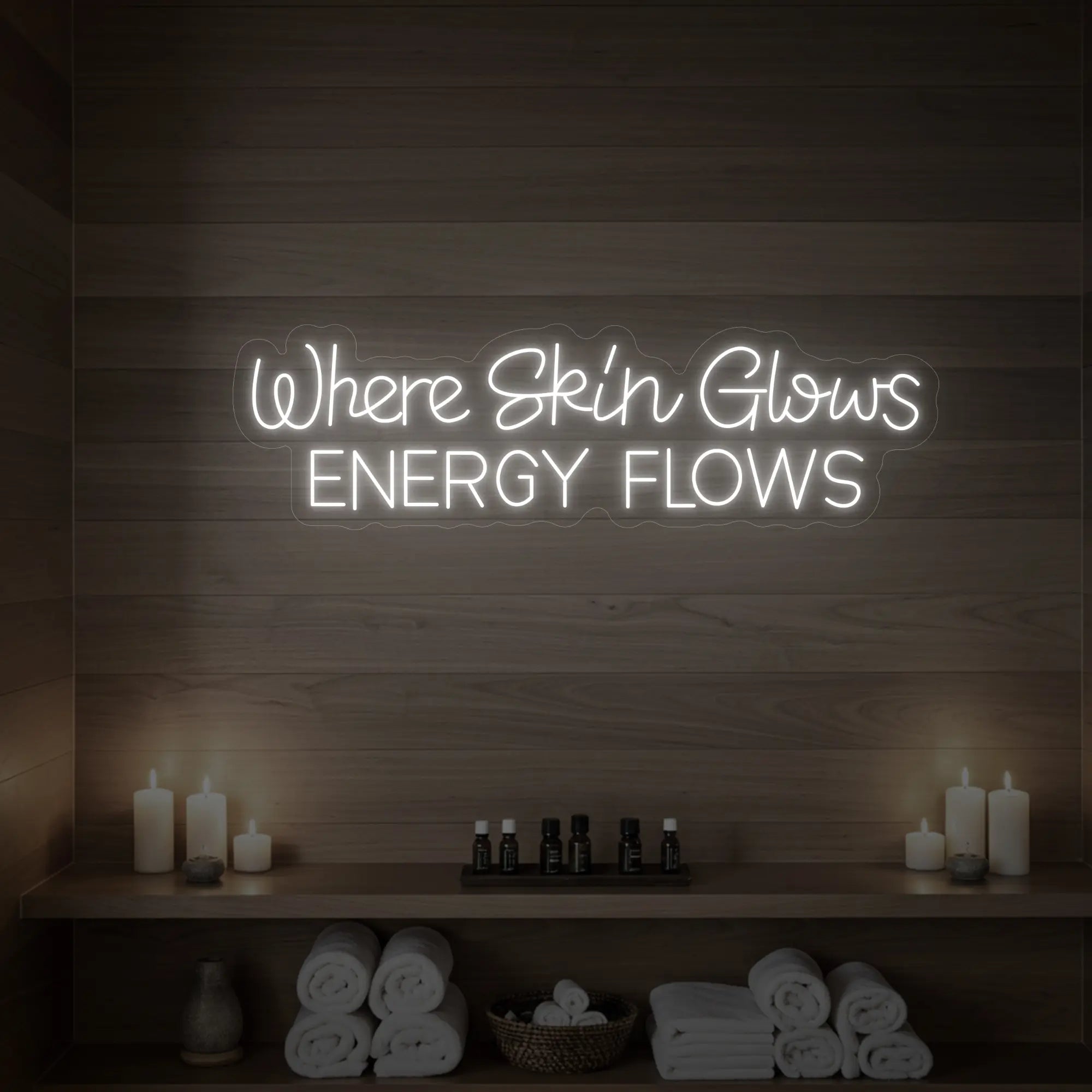 Photo of the 'Where Skin Glows, Energy Flows' neon sign glowing in cool white against a styled interior wall.