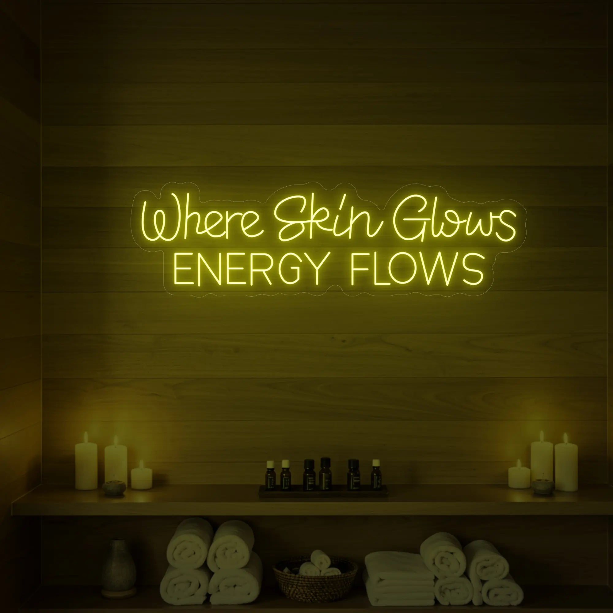 Photo of the 'Where Skin Glows, Energy Flows' neon sign glowing in lemon yellow against a styled interior wall.