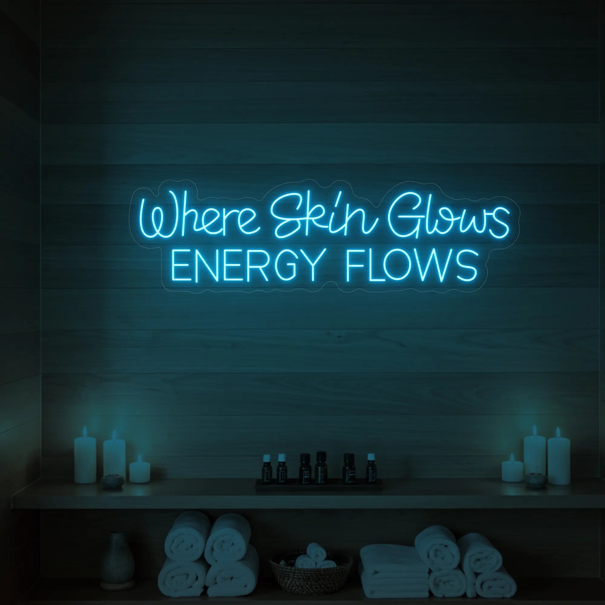Photo of the 'Where Skin Glows, Energy Flows' neon sign glowing in ice blue against a styled interior wall.