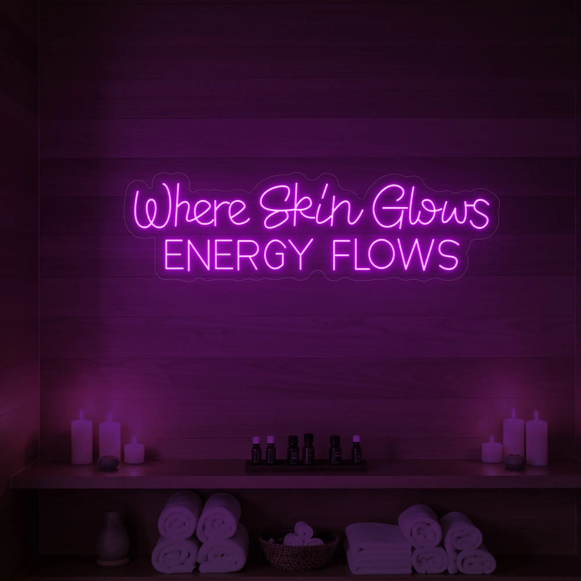Photo of the 'Where Skin Glows, Energy Flows' neon sign glowing in deep pink against a styled interior wall.