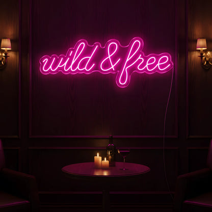 Photo of the 'Wild & Free' neon sign glowing in pink against a modern boho-inspired wall.
