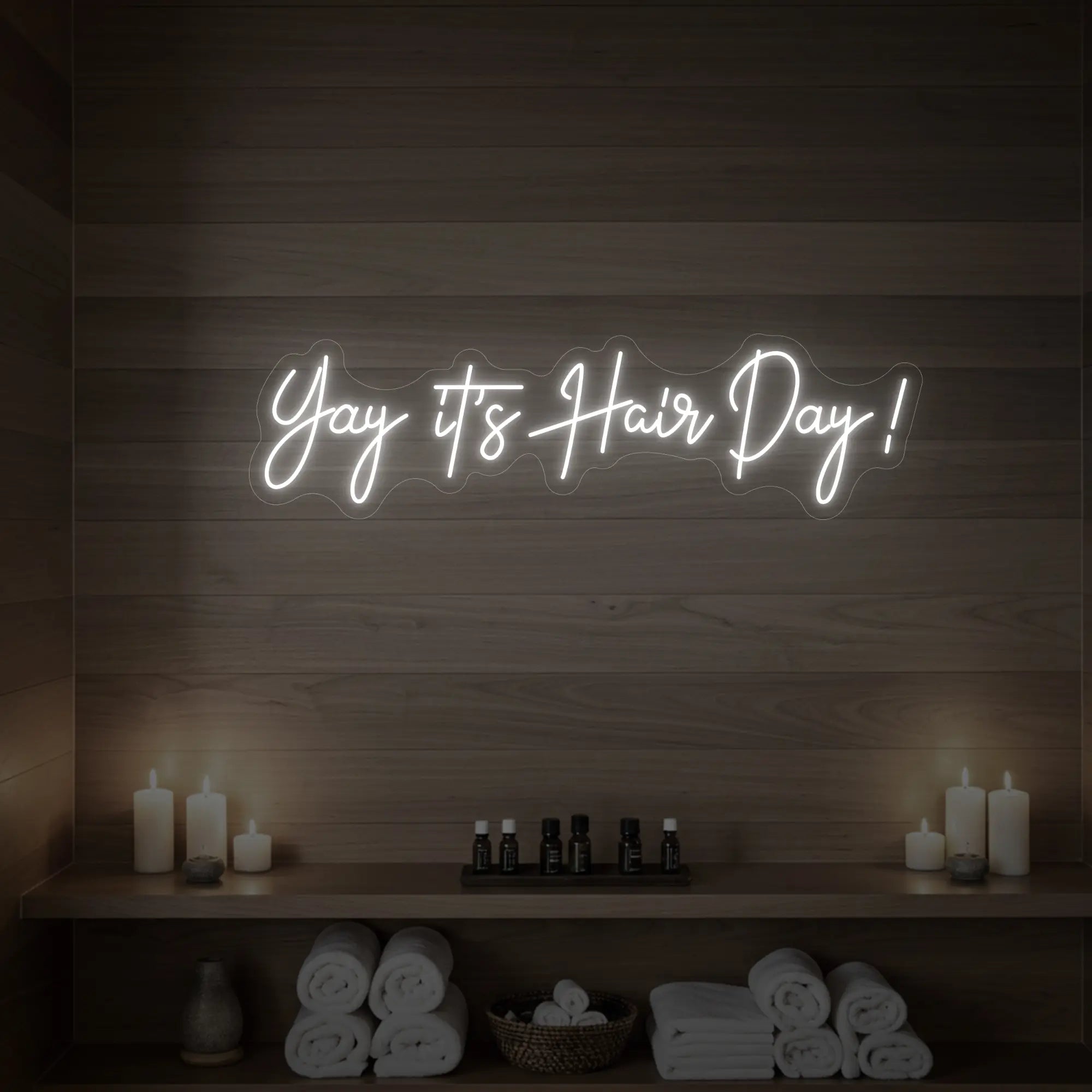 Photo of the 'Yay it’s Hair Day!' neon sign glowing in cool white against a styled interior wall.