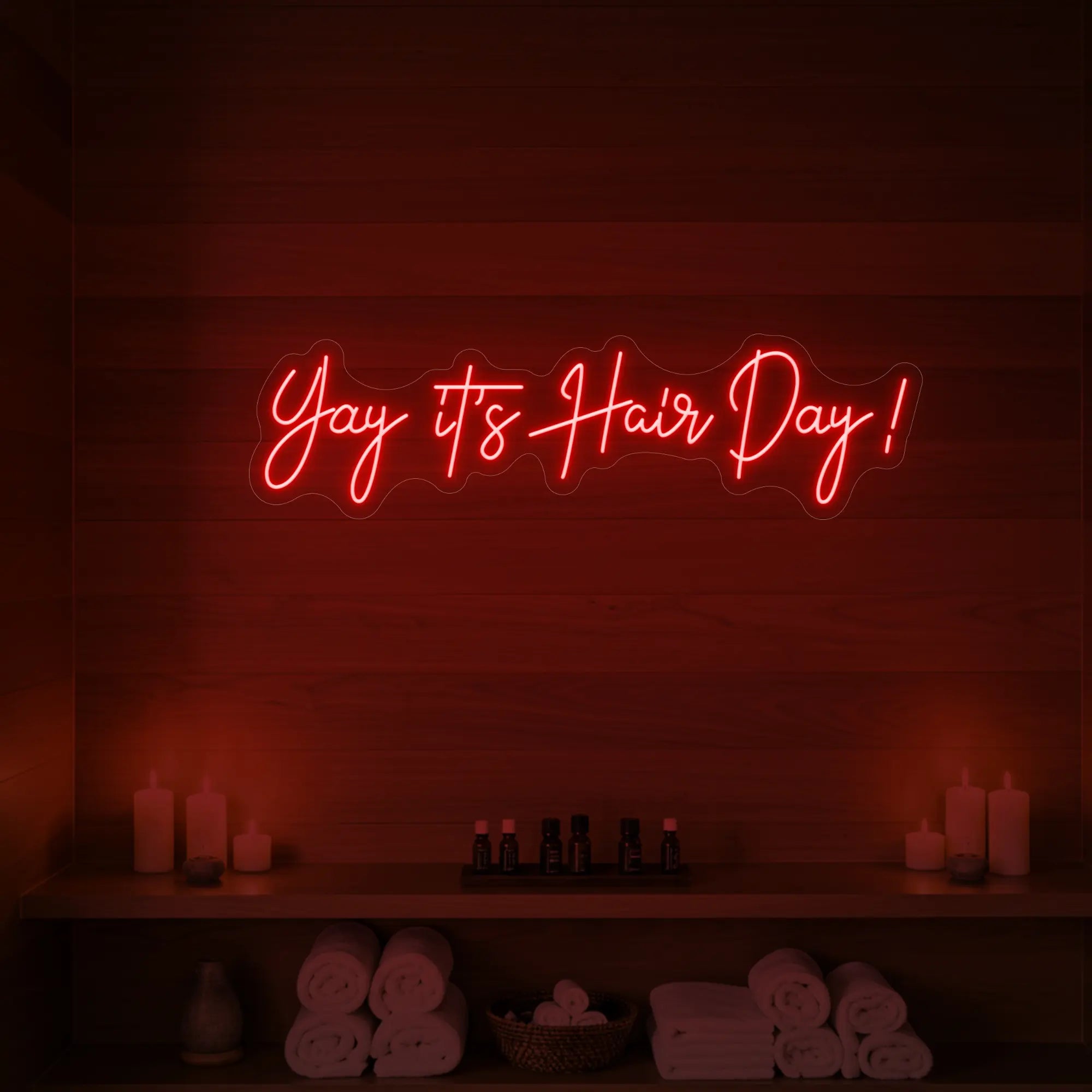 Photo of the 'Yay it’s Hair Day!' neon sign glowing in red against a styled interior wall.