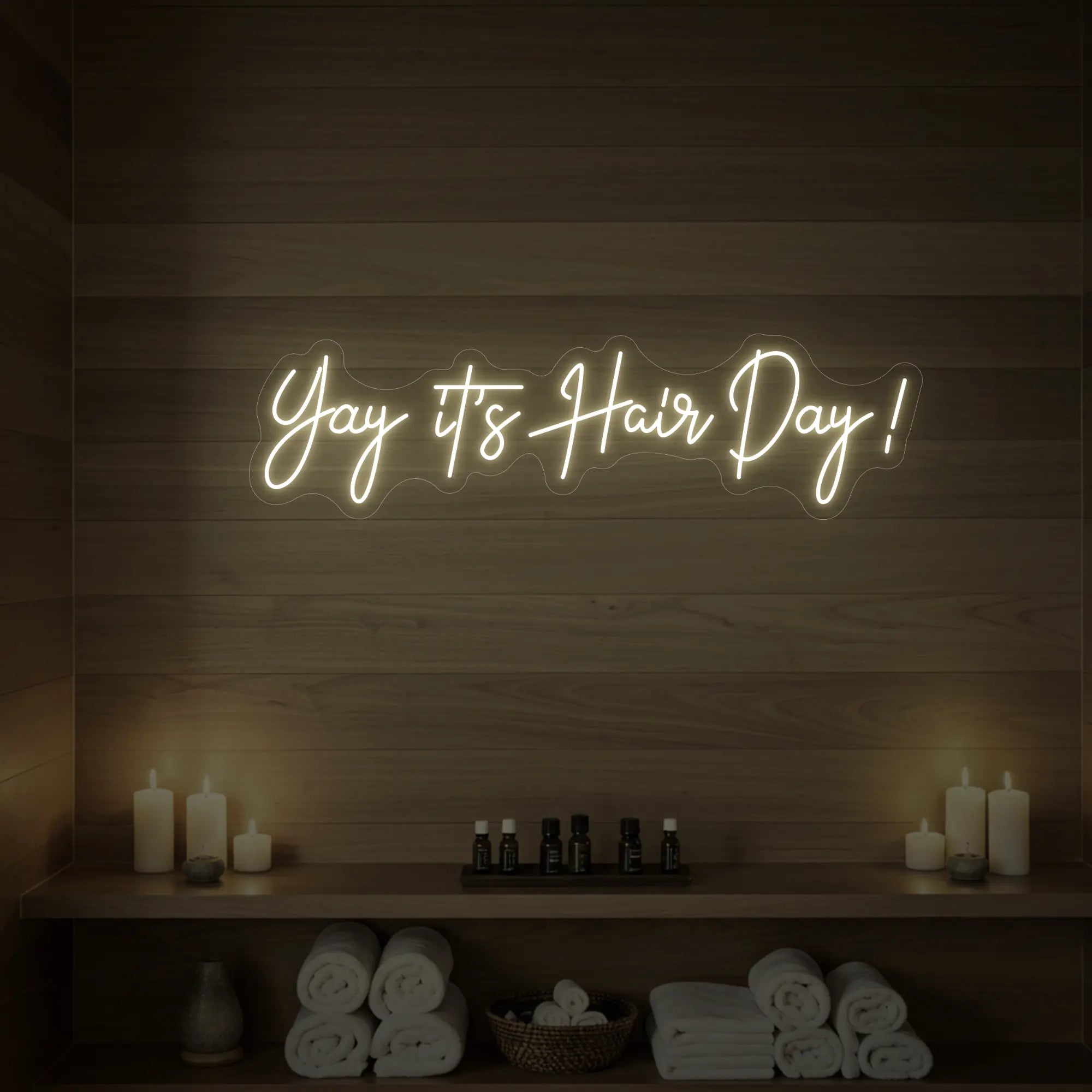 Photo of the 'Yay it’s Hair Day!' neon sign glowing in warm white against a styled interior wall.