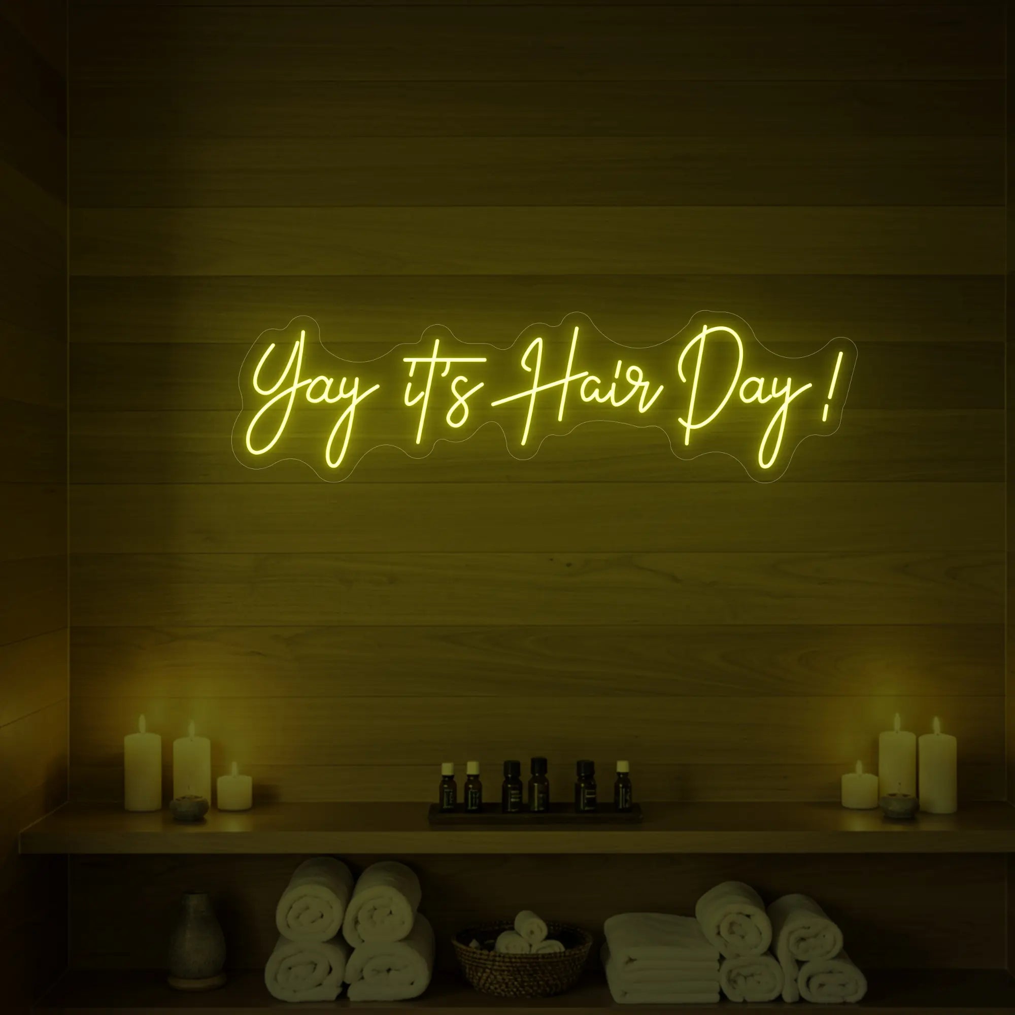 Photo of the 'Yay it’s Hair Day!' neon sign glowing in lemon yellow against a styled interior wall.