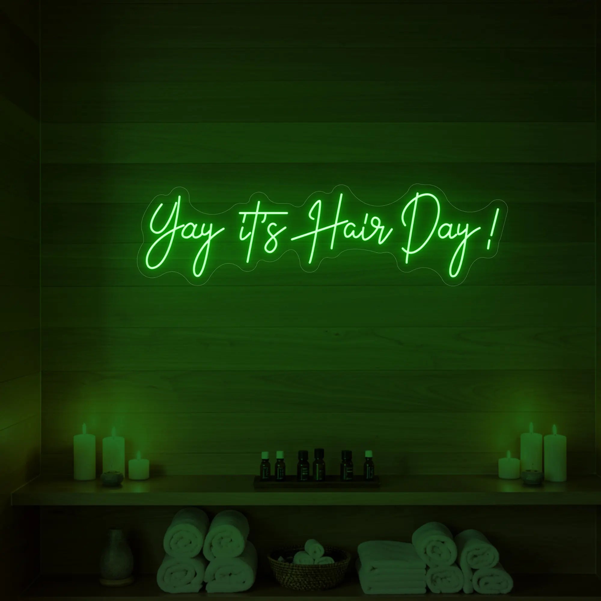 Photo of the 'Yay it’s Hair Day!' neon sign glowing in green against a styled interior wall.