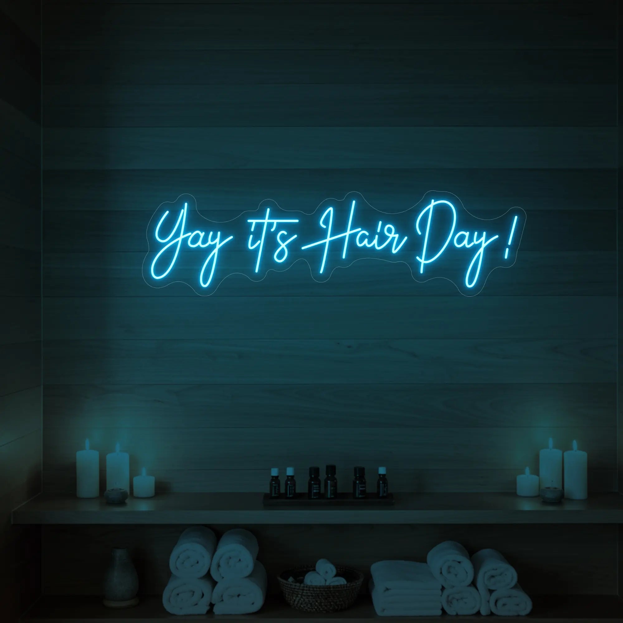 Photo of the 'Yay it’s Hair Day!' neon sign glowing in ice blue against a styled interior wall.