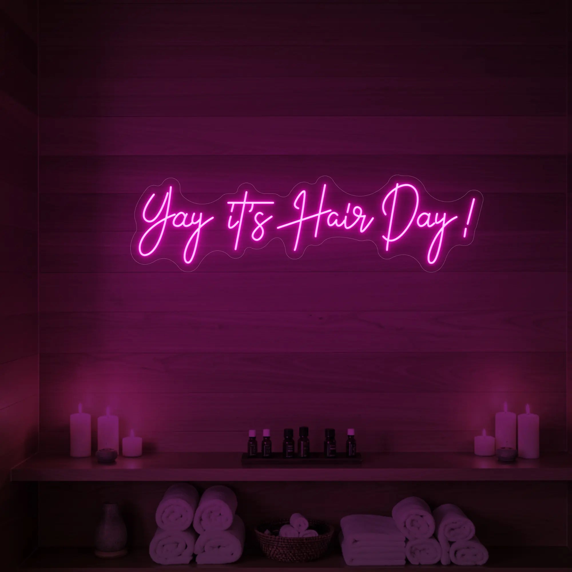 Photo of the 'Yay it’s Hair Day!' neon sign glowing in light pink against a styled interior wall.