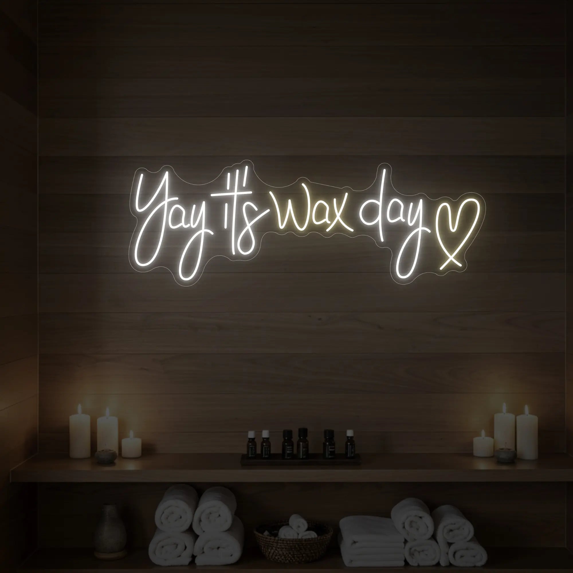 Photo of the 'Yay It’s Wax Day ❤' neon sign glowing in warm white against a styled interior wall.