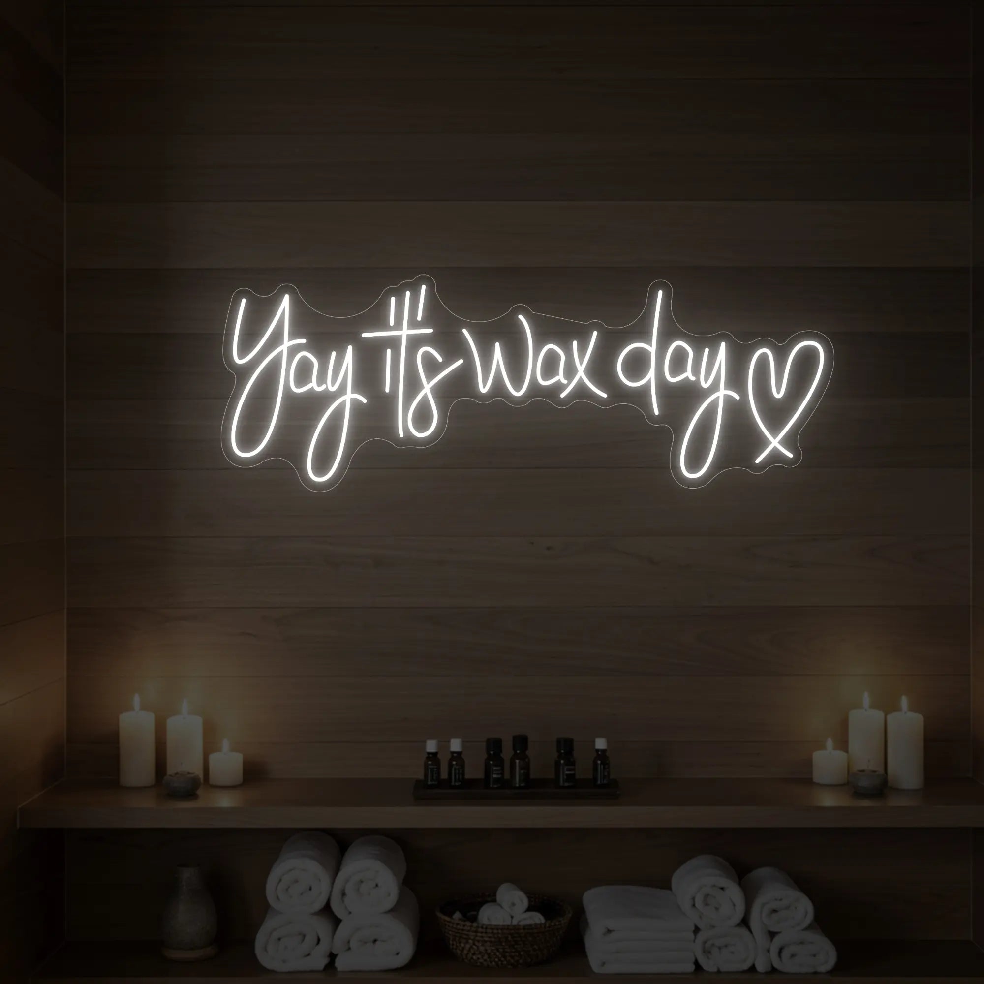 Photo of the 'Yay It’s Wax Day ❤' neon sign glowing in cool white against a styled interior wall.