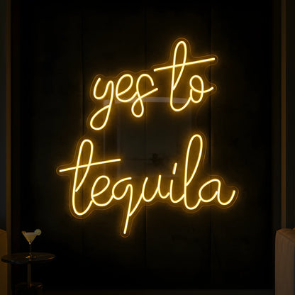 Photo of the 'Yes to Tequila' neon sign glowing in yellow against a tequila bar-inspired wall.