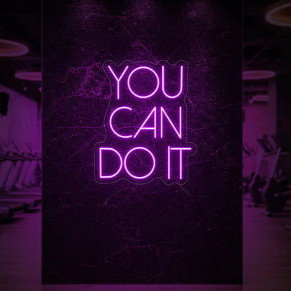 Photo of the 'YOU CAN DO IT' neon sign glowing in deep pink against a styled interior wall.