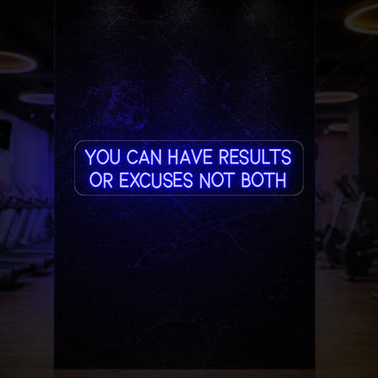 'YOU CAN HAVE RESULTS OR EXCUSES NOT BOTH' neon sign glowing in deep blue against a styled interior wall.