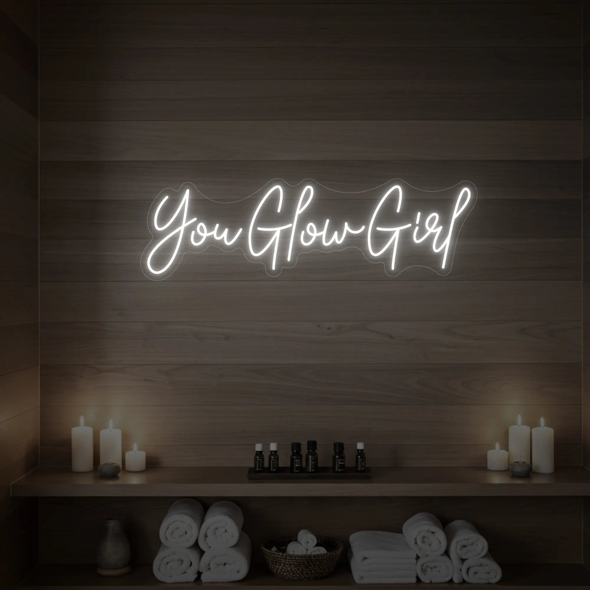 Photo of the 'You Glow Girl' neon sign glowing in cool white against a styled interior wall.