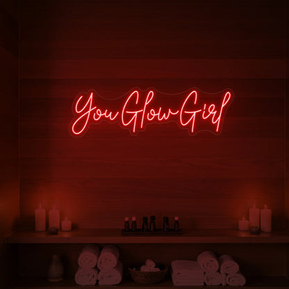 Photo of the 'You Glow Girl' neon sign glowing in red against a styled interior wall.