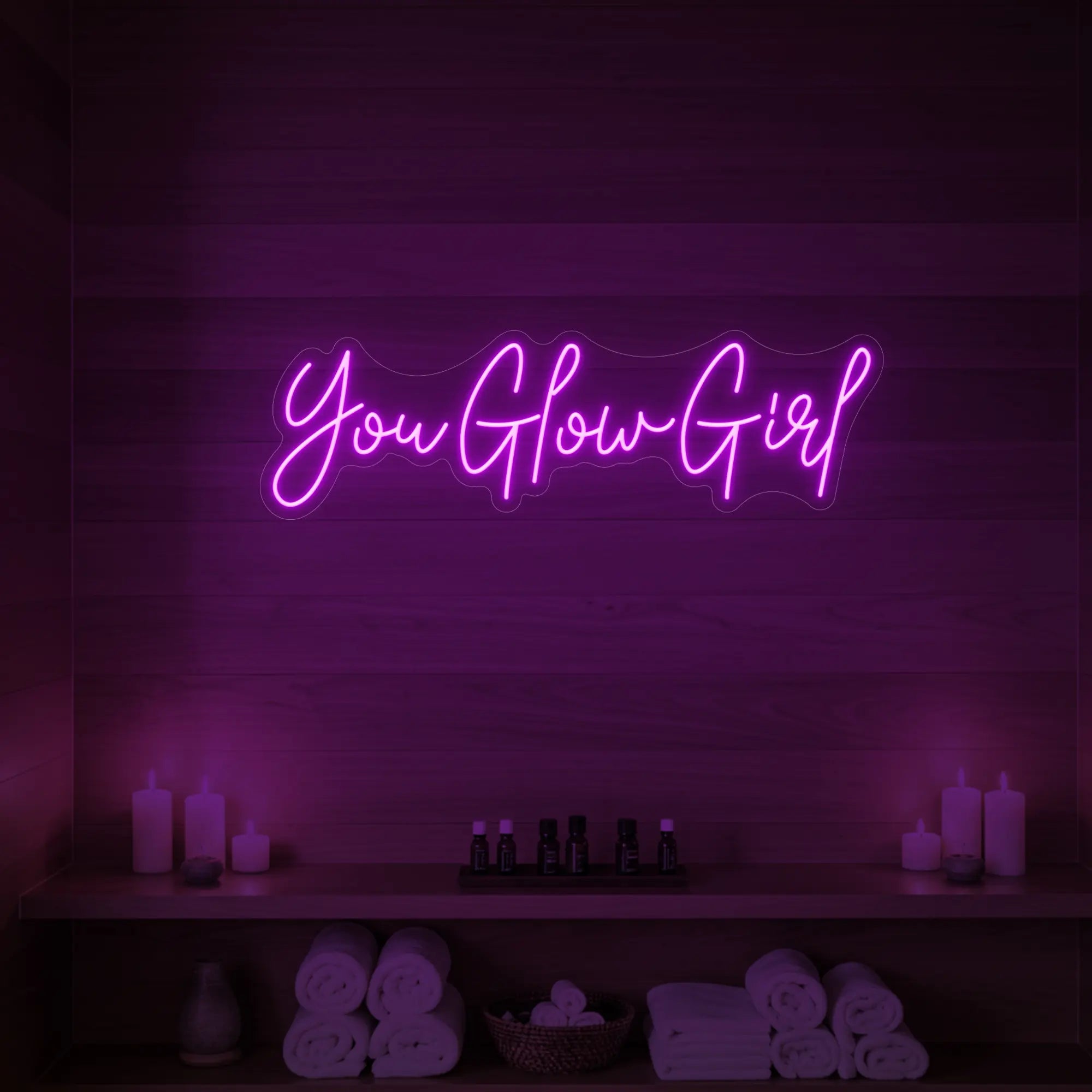 Photo of the 'You Glow Girl' neon sign glowing in deep pink against a styled interior wall.